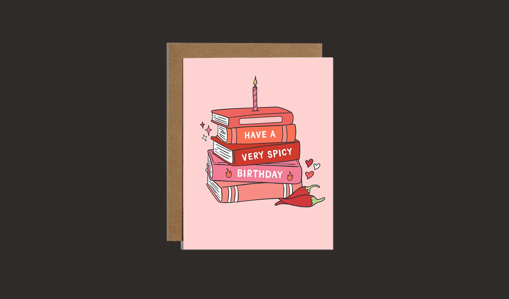 A bookish birthday card showing a stack of red books with a candle, beside its kraft envelope